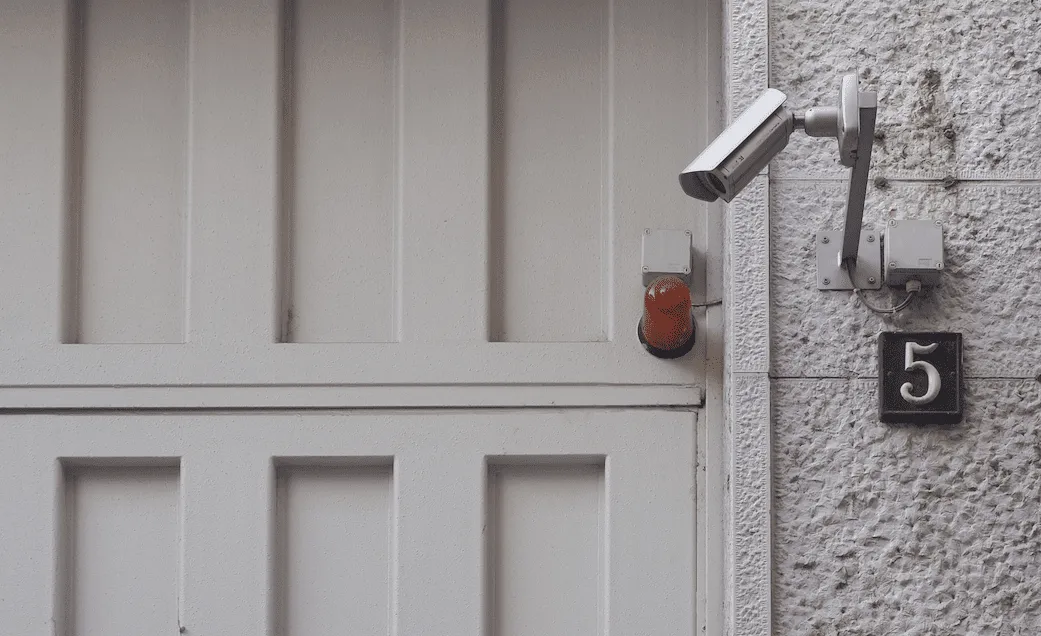A white security camera mounted outside a garage