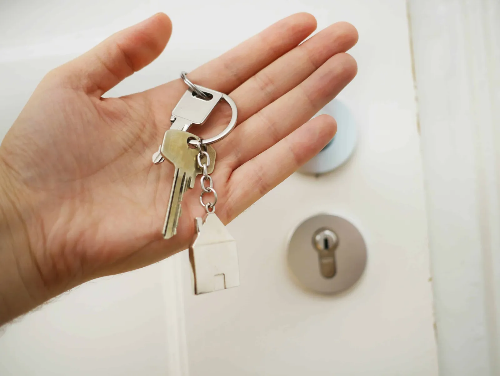 a woman holding keys standing in front of a door