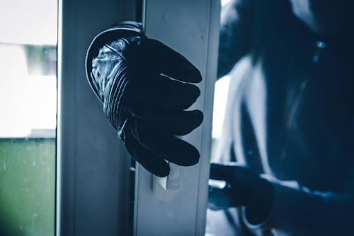 Gloved hand pushing open a door during a break-in