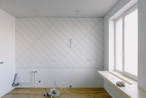 Empty room with a wall marked for cable channels and a coil of cables on the floor