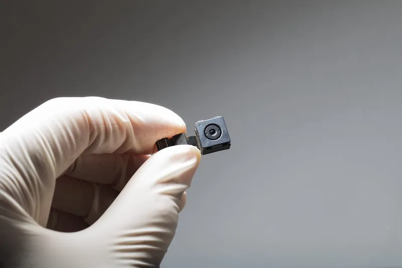 a hand holding a black and small hidden camera