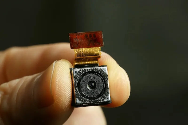 a hand holding a small hidden camera