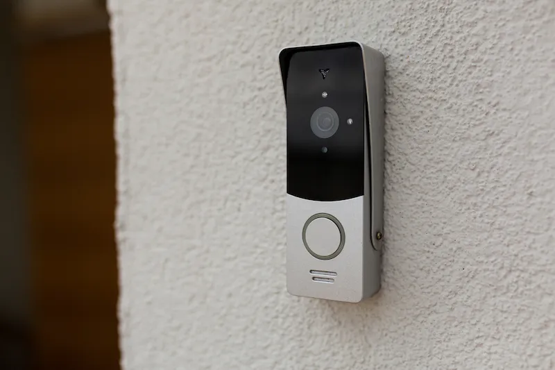 A video doorbell with a camera lens mounted on a textured wall