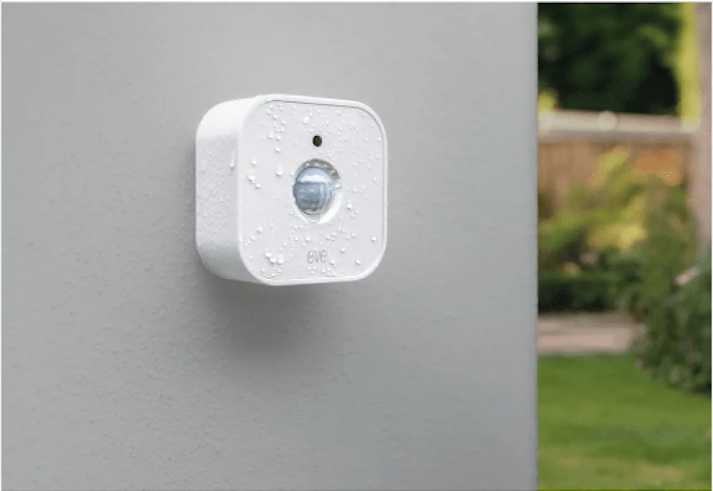 Eve Motion wireless motion sensor mounted on a wall outside, wet from rain