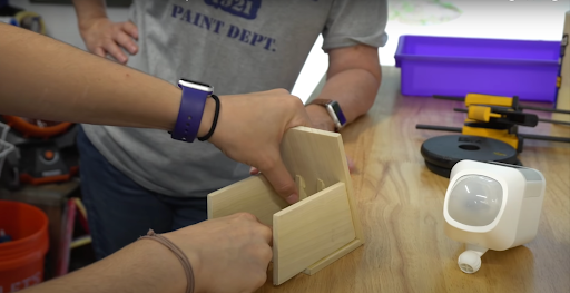 a man building a wooden bird house for security camera