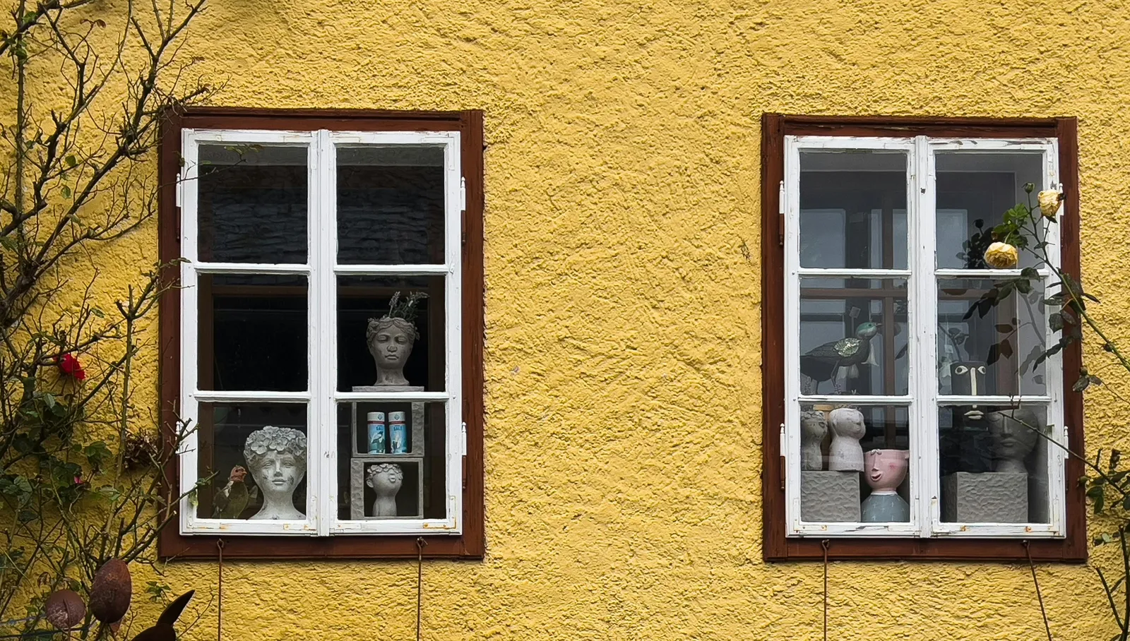 Two windows on a yellow house wall