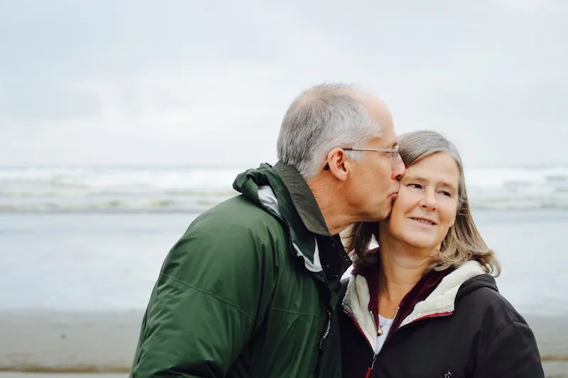 A man kissing his wife on the face.