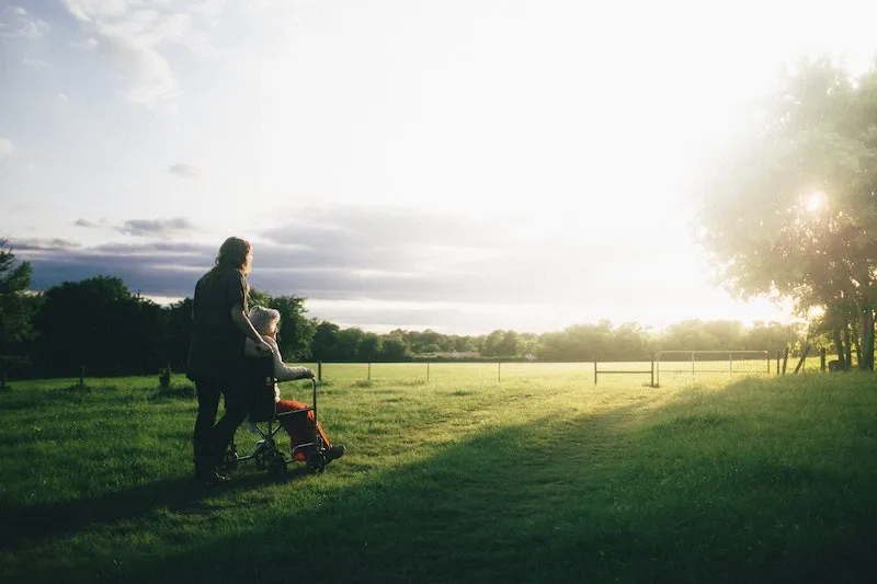 A person looks at the setting sun with their caregiver.