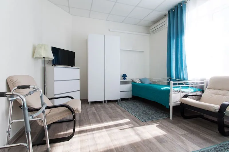 interior of a room inside a nursing home with chair, bed, and closet