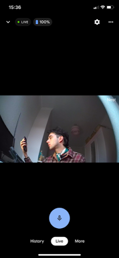 Nest Cam live feed in the Google Home app showing a man in a plaid shirt holding a phone