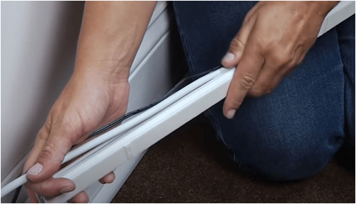 Hands fitting a white cord cover along a baseboard.