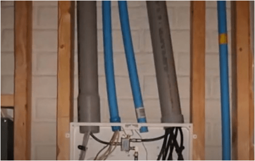 Flexible conduit tubes running between wall studs into a junction box.
