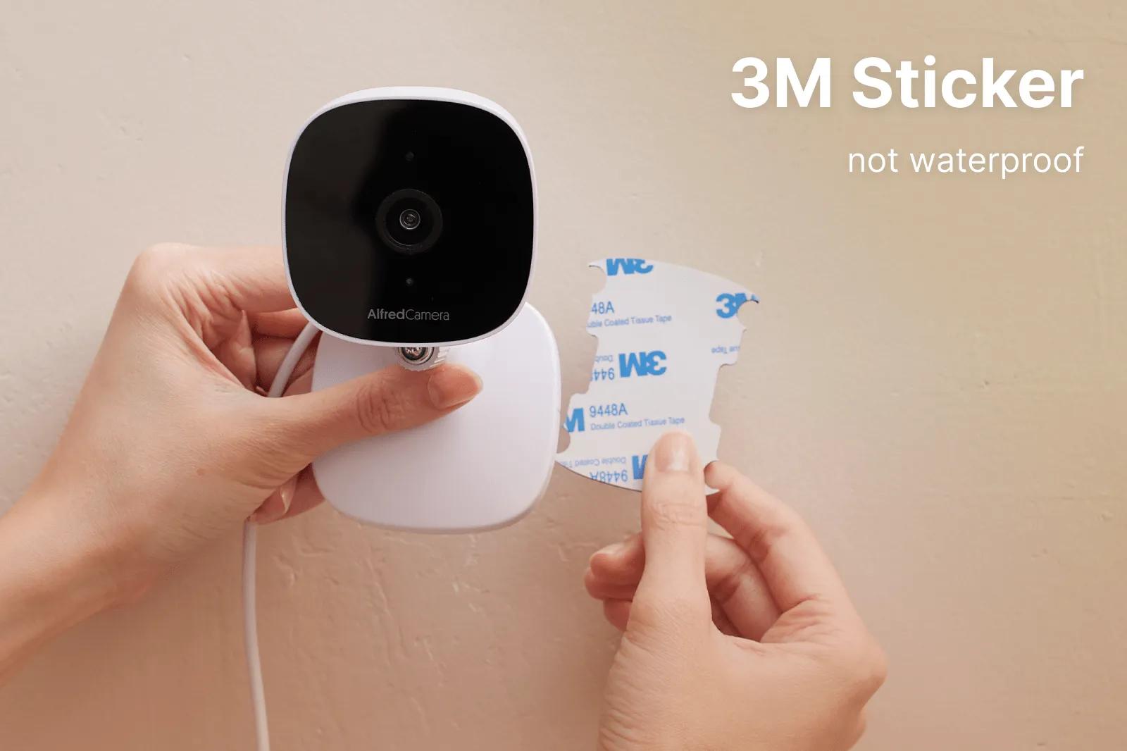 Hands sticking AlfredCam Plus to a wall with a 3M adhesive sticker
