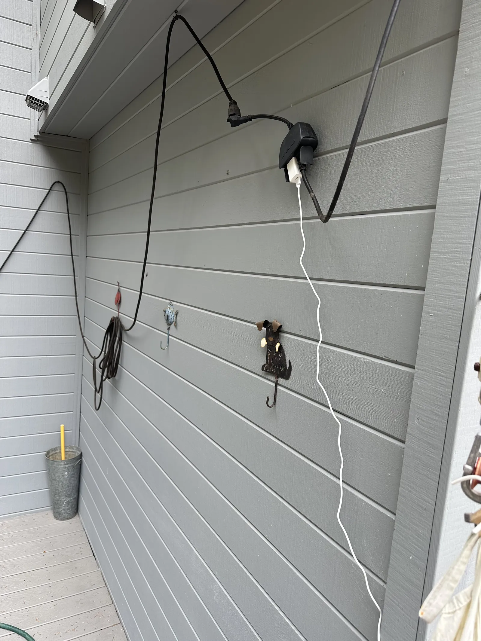 Power cable and adapter running along a grey exterior wall.
