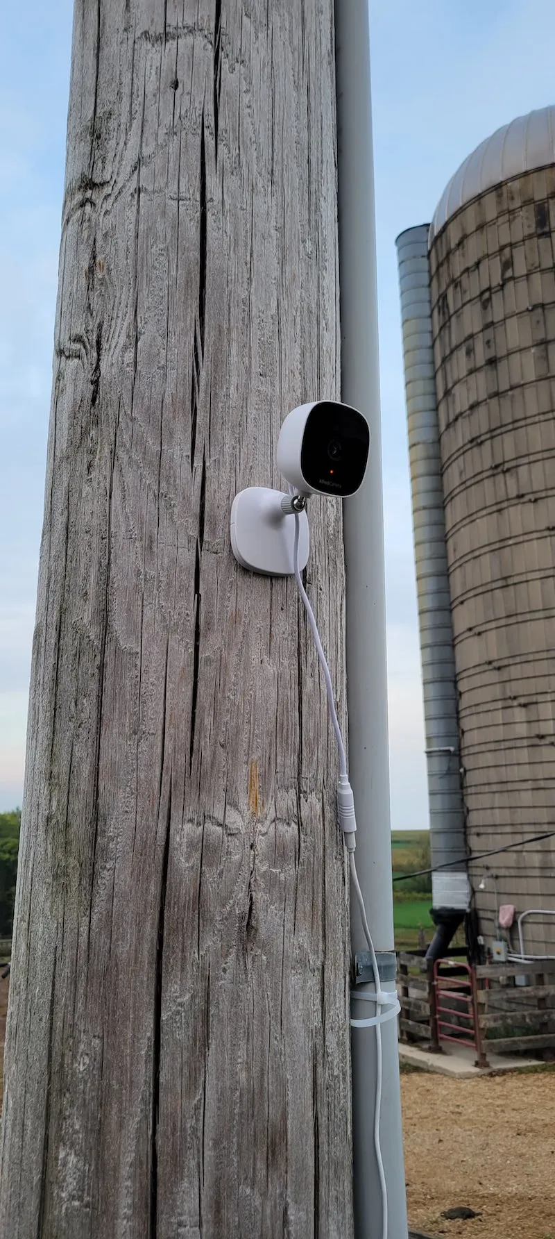 AlfredCam Plus screwed to a wooden utility pole, with a silo in the background.