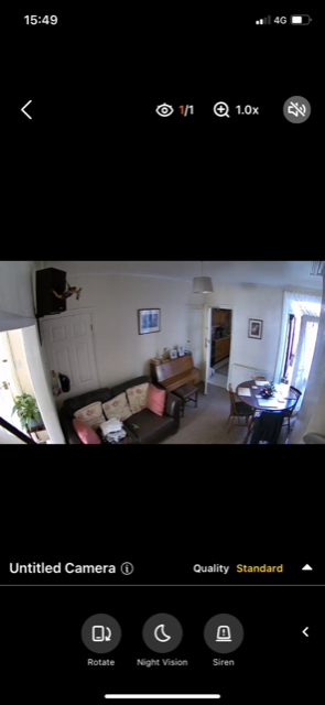 AlfredCamera live view of a living room with a sofa and dining table.